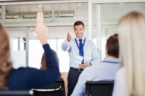 image of an instructor calling on a student raising their hand.
