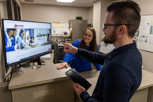 image of a two employees. One is looking at a computer